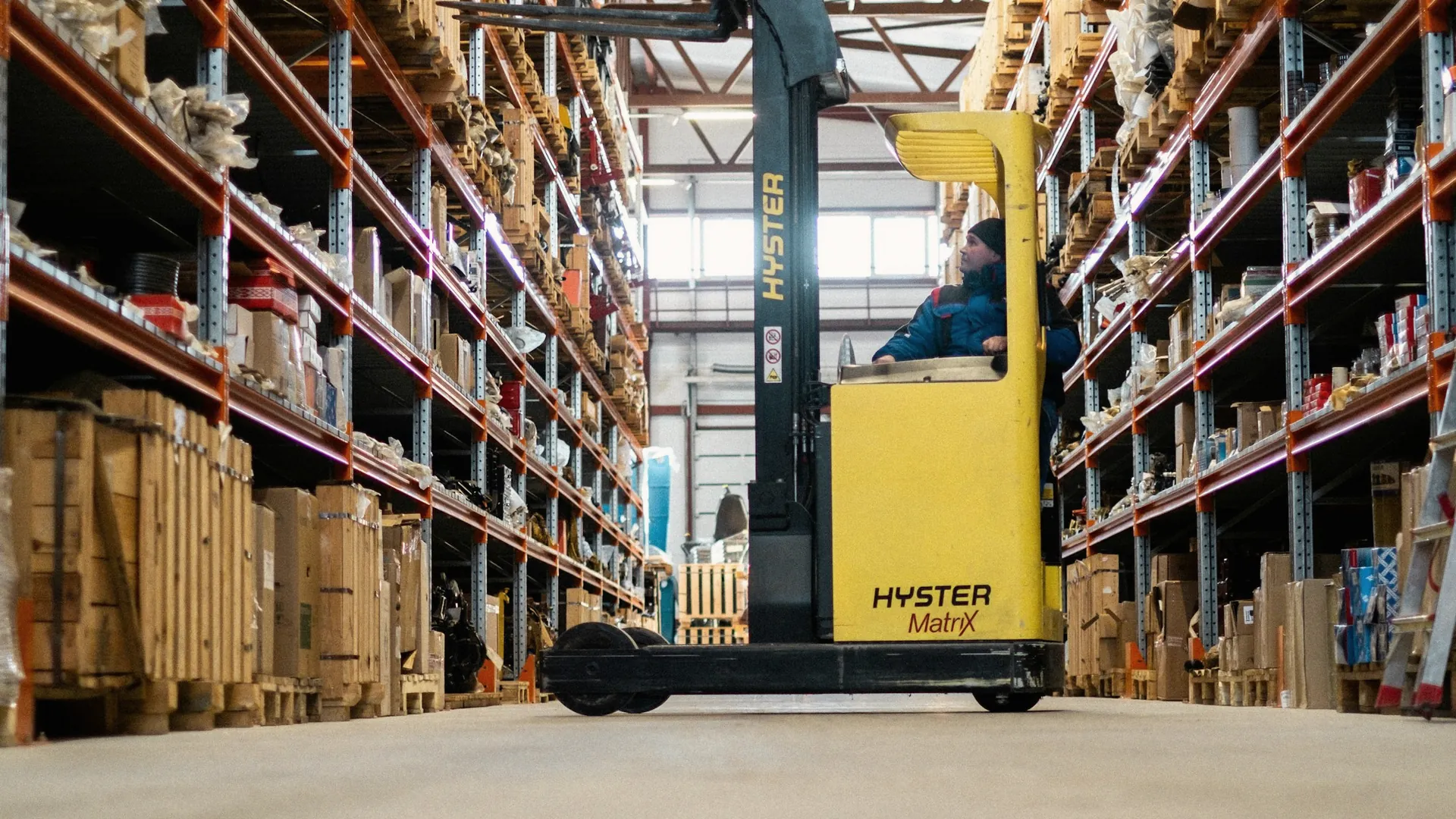 Un cariste manœuvre un chariot élévateur entre les rayonnages d’un entrepôt