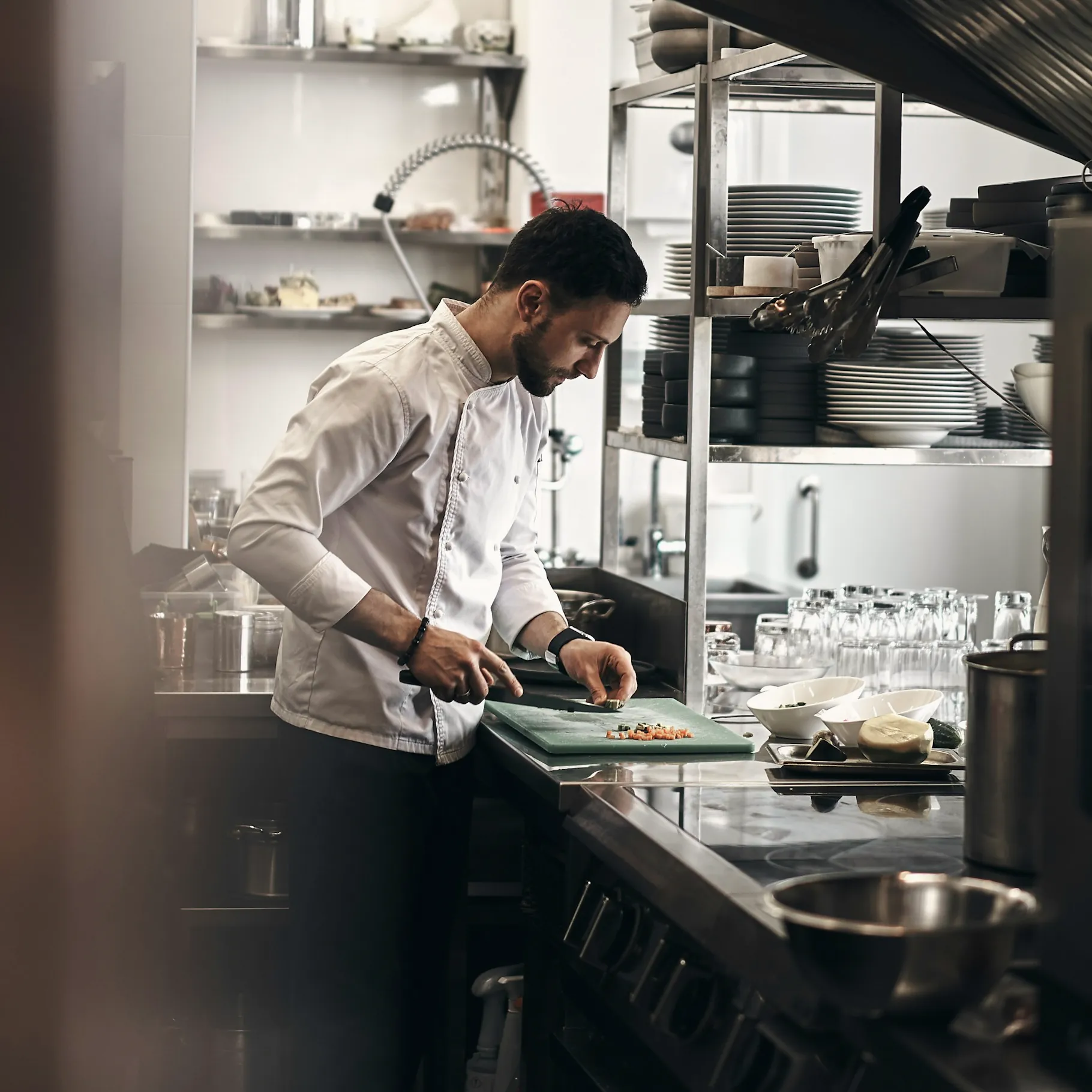 Un cuisinier prépare des légumes au plan de travail d’une cuisine professionnelle