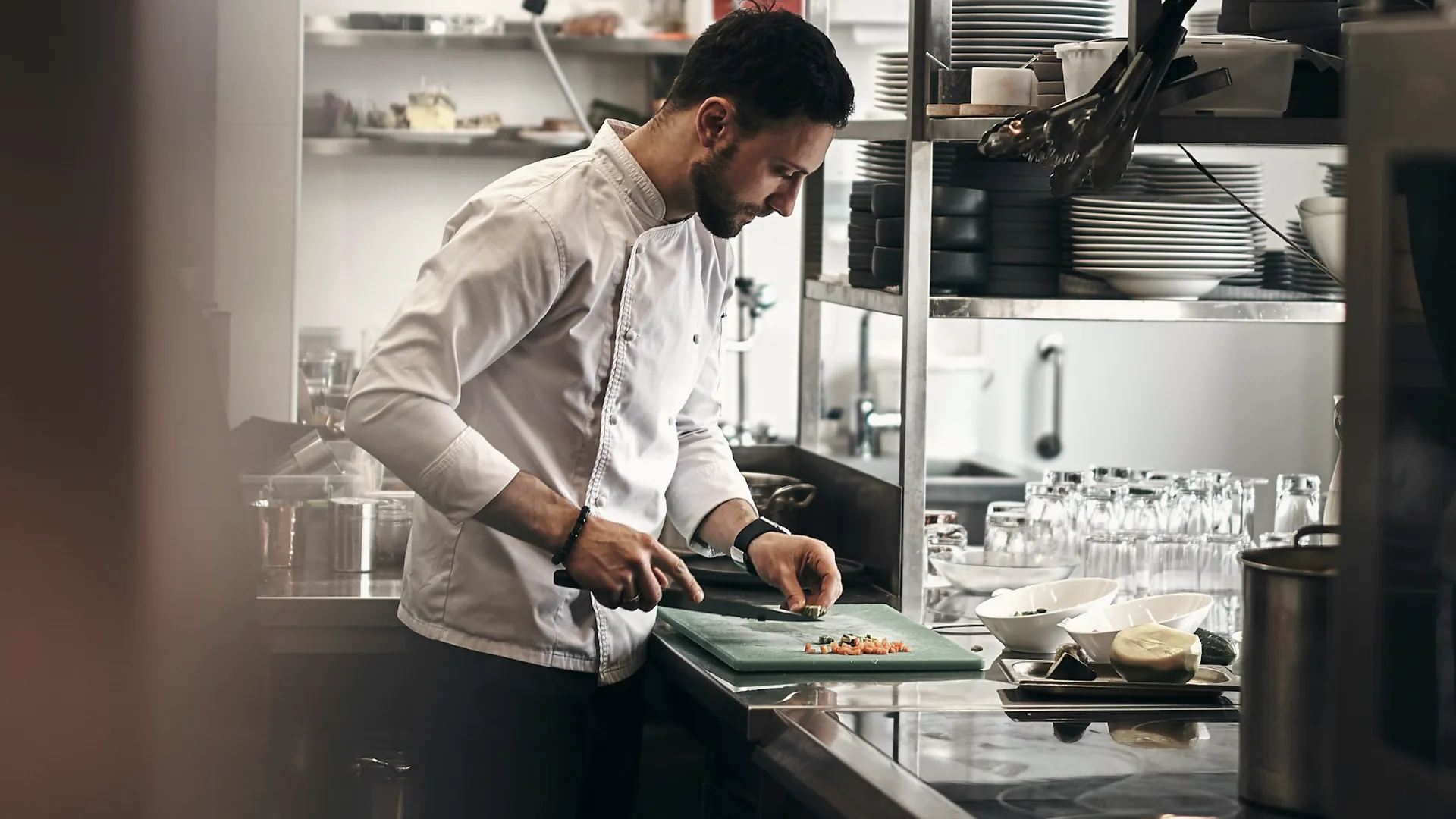 Un cuisinier prépare des légumes au plan de travail d’une cuisine professionnelle