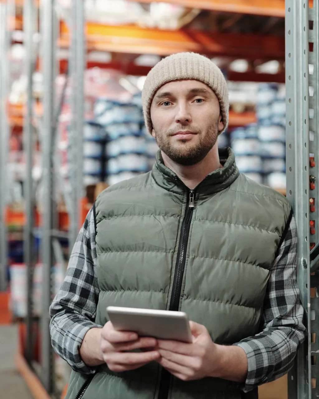 Un professionnel de la logistique tient une tablette dans une allée d’entrepôt