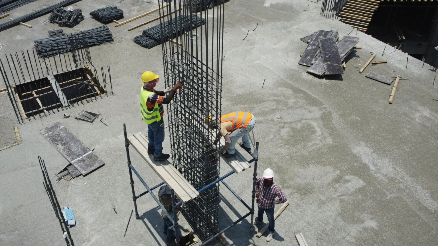 Des ouvriers assemblent les armatures d’une structure en béton sur un chantier